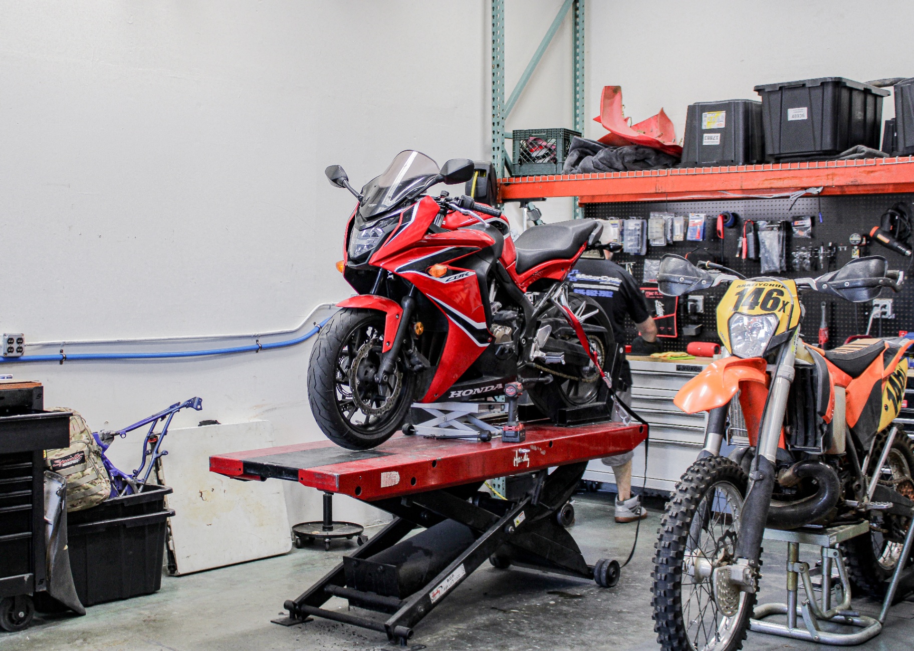 Technician working on a sport bike in a modern motorcycle workshop